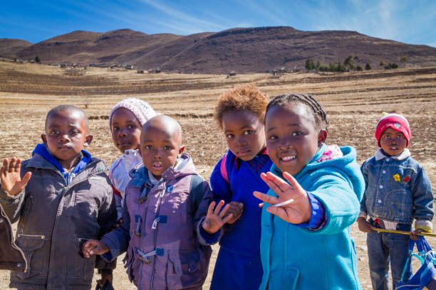 Leribe, Lesotho - August 10, 2016: Friendly children walk home from school in beautiful winter scenery of south Africa's mountain kingdom; free, compulsory universal primary education began in 2000