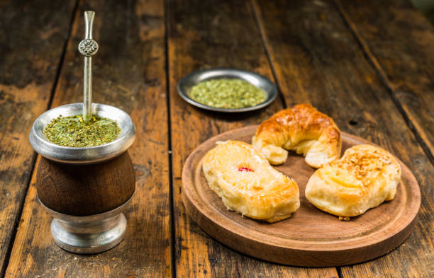 традиционный аргентинский чай йерба мате в калабаш-тыкве с палкой бомбиллы и аргентинскими десертами из выпечки на деревянном фоне - argentina buenos aires yerba mate gaucho стоковые фото и изображения