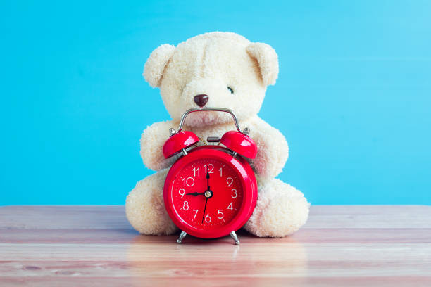 istock Bear and red watch placed on a blue wooden table. 901777072