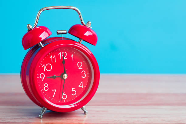 reloj rojo colocado en la mesa de madera sobre fondo azul - daylight savings fotografías e imágenes de stock