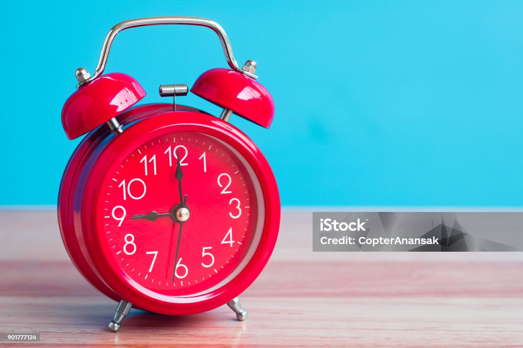 Red clock placed on wooden table on blue background Savings Stock Photo