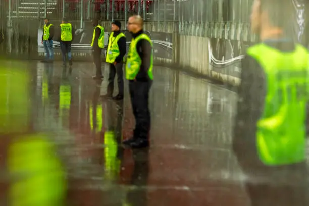 Security employees standing in a line at a stadium on a sporting event at night.