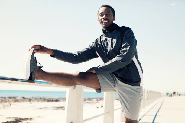 istock Smiling young man stretching leg on sunny day 901804140