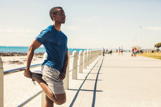 istock Athlete stretching leg on promenade against sky 901804326