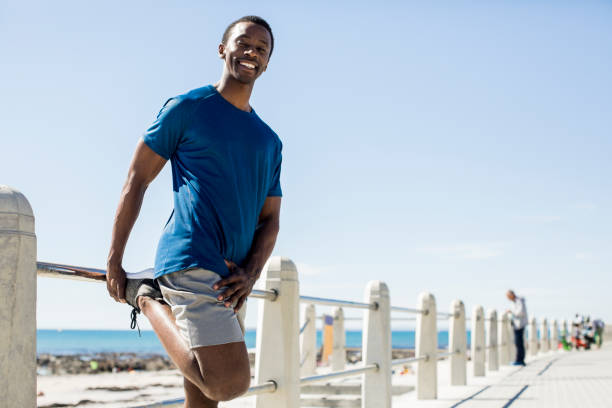 istock Smiling man stretching leg by railing against sky 901804392