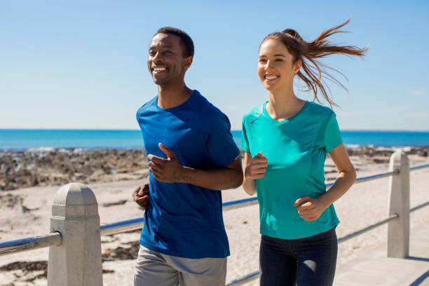 Happy friends jogging together at the beach