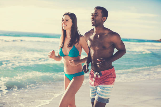 istock Multi-ethnic couple running at beach against sky 901806048