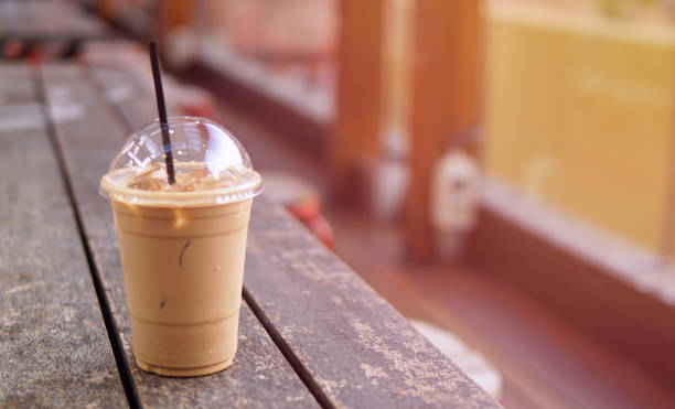istock Ice coffee latte in takeaway cup on wood table. Takeaway ice latte in plastic cup with straw on wood table. Cafe shop background with ice latte on wood table 901806446