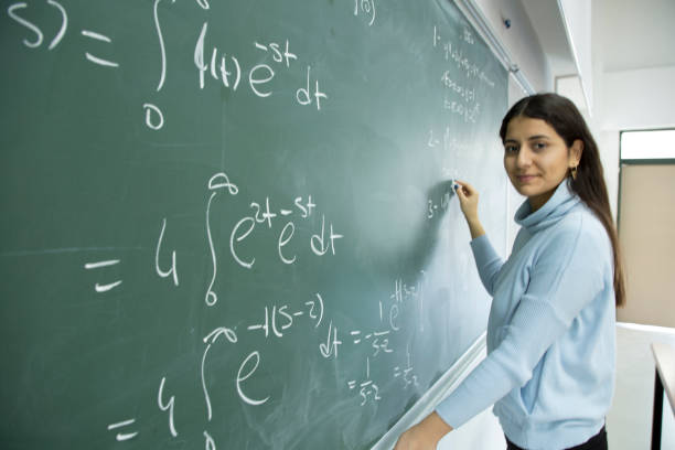 istock Female Student writing mathematical formula in front of the blackboard 901810040