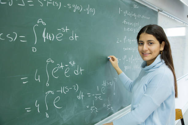 istock Female Student writing mathematical formula in front of the blackboard 901810056