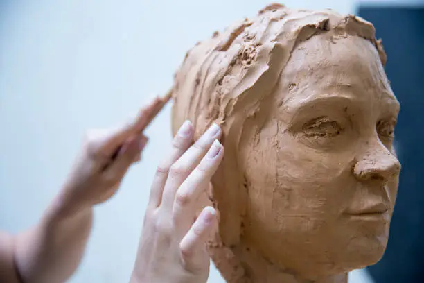 Photo of Artist working on clay sculpture in art studio