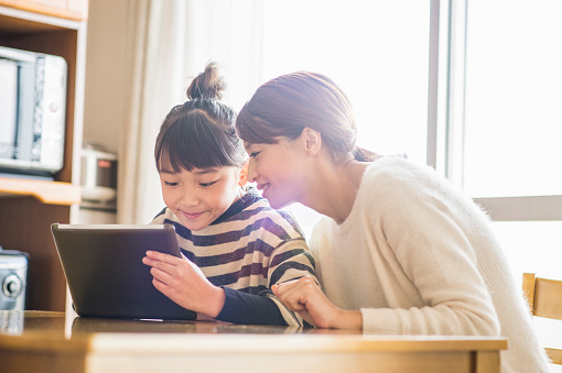 Madre e hija jugando con una tableta digital en habitación photo