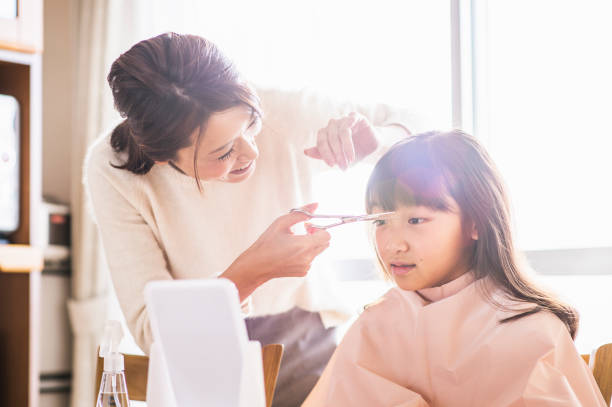 istock Mother cutting her daughter's hair on the day off. 901816644