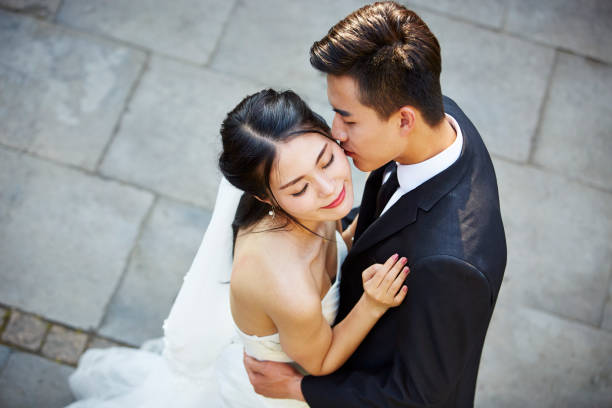 young asian bride and groom embracing kissing dancing in open air, high angle view.