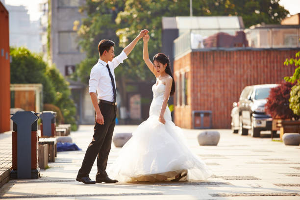 asian newlywed dancing outdoors young asian bride and groom in wedding dress dancing in parking lot. malay couple full body stock pictures, royalty-free photos & images