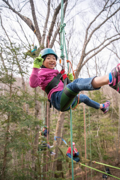 istock Young girl hanging on tree with rope 901828660