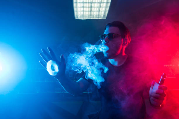 istock A man smokes a cigarette and lets out smoke in a nightclub. 901828962
