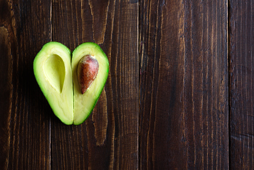 Heart shaped avocado half on wooden background