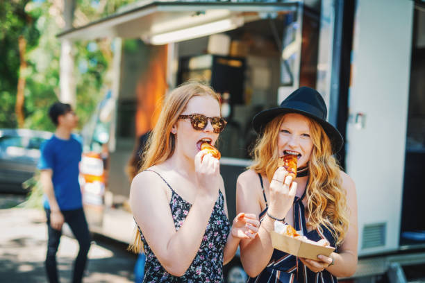 Girlfriends eating food from food van