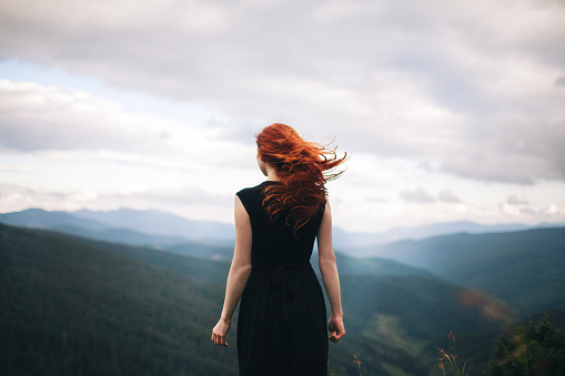 Mujer en vestido negro caminando en las montañas y mirando a ver photo