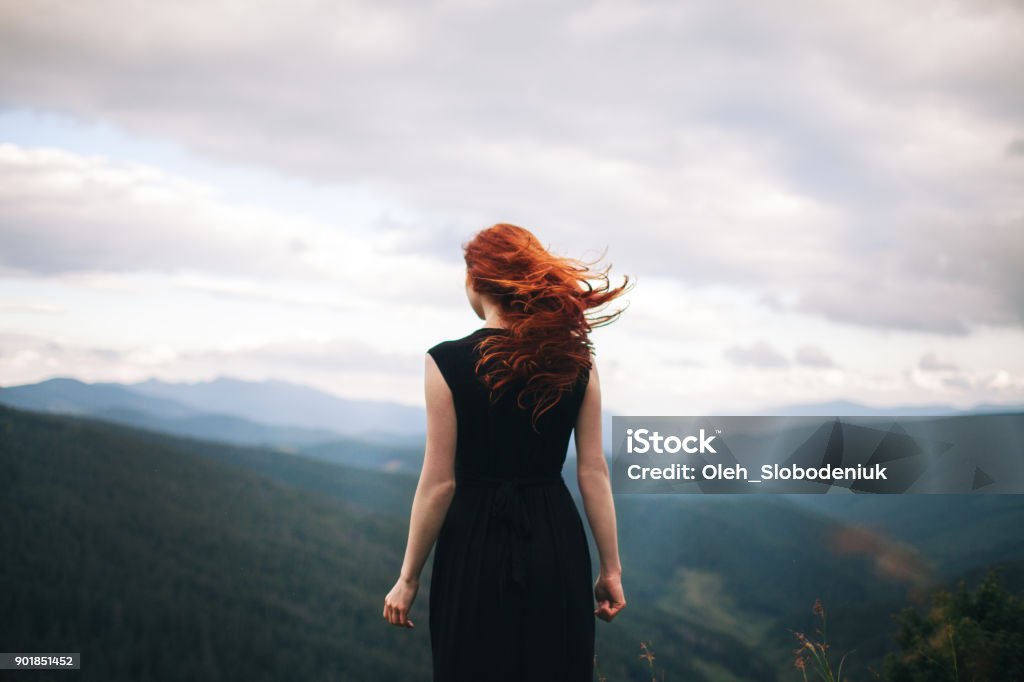 Woman in black dress walking in the mountains and looking at view Young Caucasian Woman in black dress walking in the mountains and looking at view Women Stock Photo