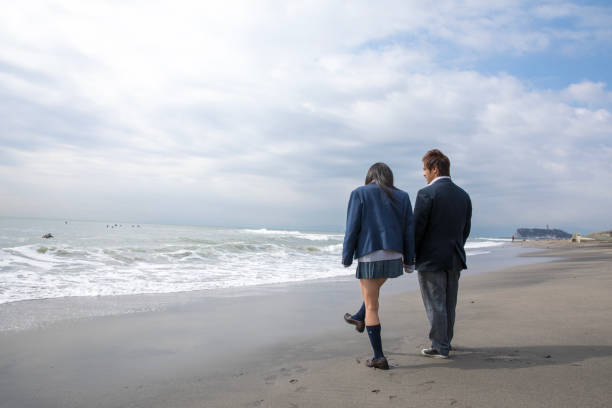 High school student couple walking on beach