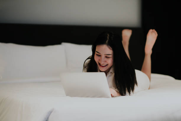 istock Asian woman is using laptop with her work on bed 901857306