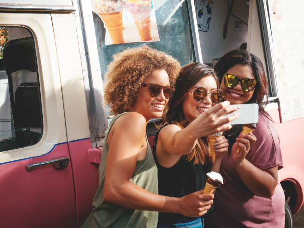 Three girls eating ice creams near the ice cream truck in Australia Three beautiful diverse young women eating ice cream near the ice cream truck and taking selfie ice cream van stock pictures, royalty-free photos & images