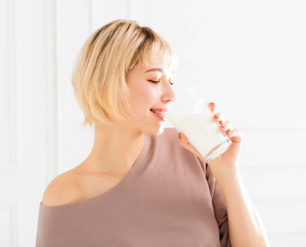 istock smiling young woman drinking milk 901858396