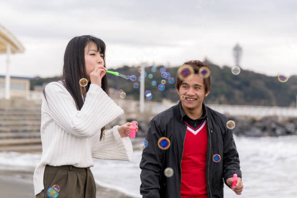 istock High school student couple playing with soap bubbles on beach 901861764