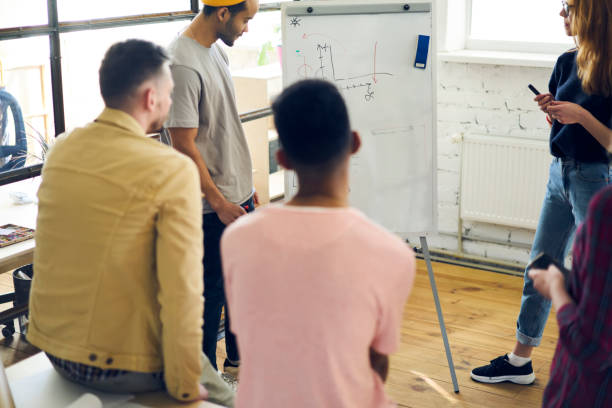 istock International group of talented team members analyzing information from board and solving problems during brainstorming session standing in office,hipsters thinking about creative ideas indoors 901863484