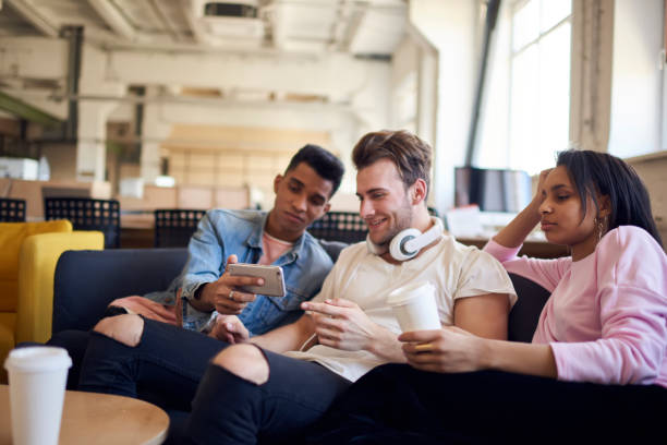 istock Afro american male internet user showing mobile application for making funny photos on modern telephone devices to friends enjoying leisure and free time during coffee break sitting in loft interior 901863538