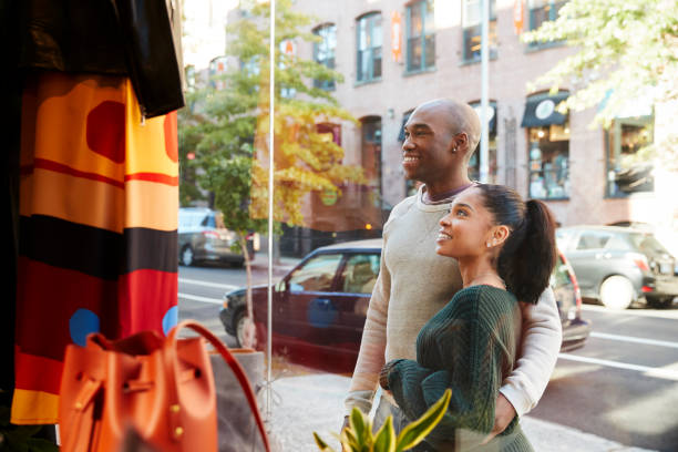 Smiling couple looking in a clothes shop window Smiling couple looking in a clothes shop window window shopping stock pictures, royalty-free photos & images