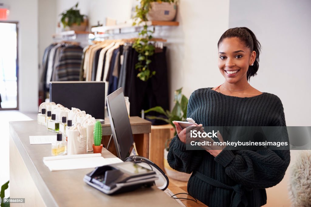 Assistante souriante sur le comptoir dans le magasin de vêtements - Photo de Magasin libre de droits