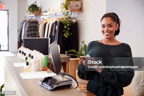 Photo libre de droit de Assistante Souriante Sur Le Comptoir Dans Le Magasin De Vêtements banque d'images et plus d'images libres de droit de Magasin