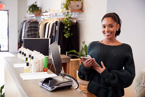 Female assistant smiling from the counter in clothing store