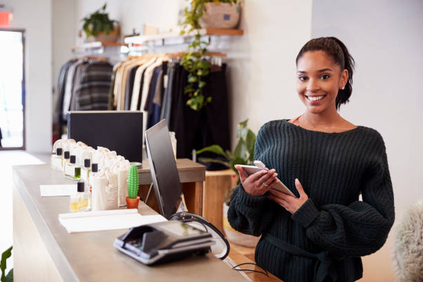 Female assistant smiling from the counter in clothing store Female assistant smiling from the counter in clothing store clothing store stock pictures, royalty-free photos & images