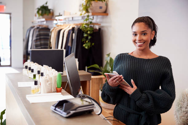 asystentka uśmiechnięta z lady w sklepie odzieżowym - clothing store sales clerk usa clothing zdjęcia i obrazy z banku zdjęć