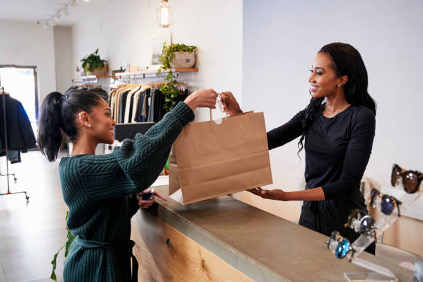 Woman serving customer at the counter in a clothing store Woman serving customer at the counter in a clothing store clothing store stock pictures, royalty-free photos & images