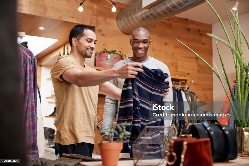 Two young men holding up clothes to look at in clothes shop Shopping Stock Photo