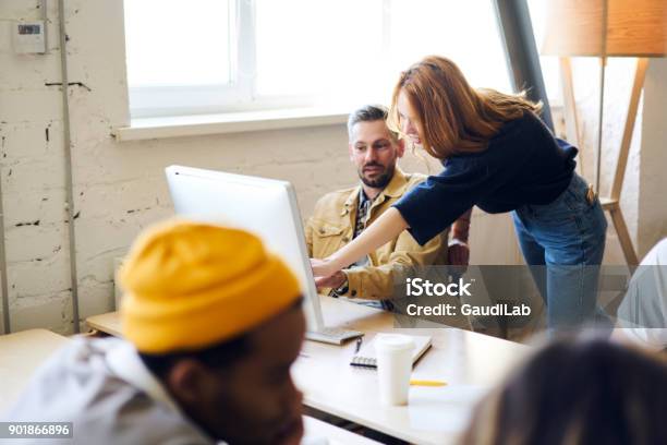 Professional Male And Female Colleagues Talking To Each Other Pointing On Advantages Of New Application Installed On Modern Computer Mature Coach Feeling Confused With Bad Internet Connection Stock Photo - Download Image Now