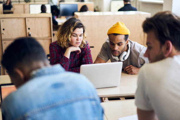 istock Young students watching movie on laptop computer spending free time on campus while their classmates preparing homework tasks, concentrated colleagues updating content on website uploading files 901866926