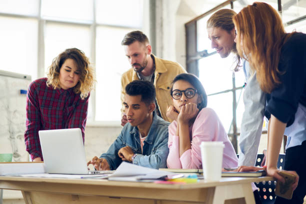 istock Skilled male IT developer presenting to colleagues his new application for digital devices consulting about advantages in use, diversity group of coworkers watching promotional video on laptop 901866938