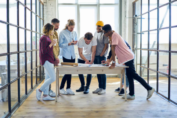 istock Male and female colleagues having brainstorming session creating architectural project working with blueprints, young professionals making researchers and analyzing accountings on informal meeting 901866990