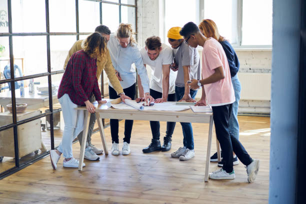 istock Young crew of creative architects drafting  together making planning of project checking accounts and blueprints drawing in coworking office, diversity group of trainees brainstorming on sketch 901867016