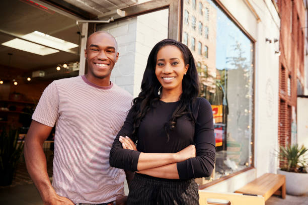 Young couple smiling to camera outside their clothes shop Young couple smiling to camera outside their clothes shop african american business couple stock pictures, royalty-free photos & images