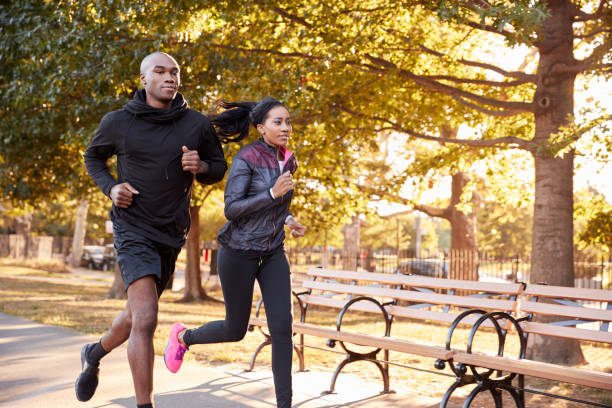 young black couple jogging in a brooklyn park, three quarter length - tree quarter length imagens e fotografias de stock