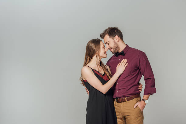 istock elegant young couple smiling each other isolated on grey 901870946