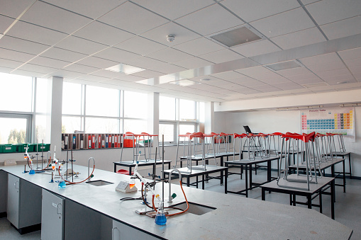 An empty school science room with the stools on the desks ready for cleaning