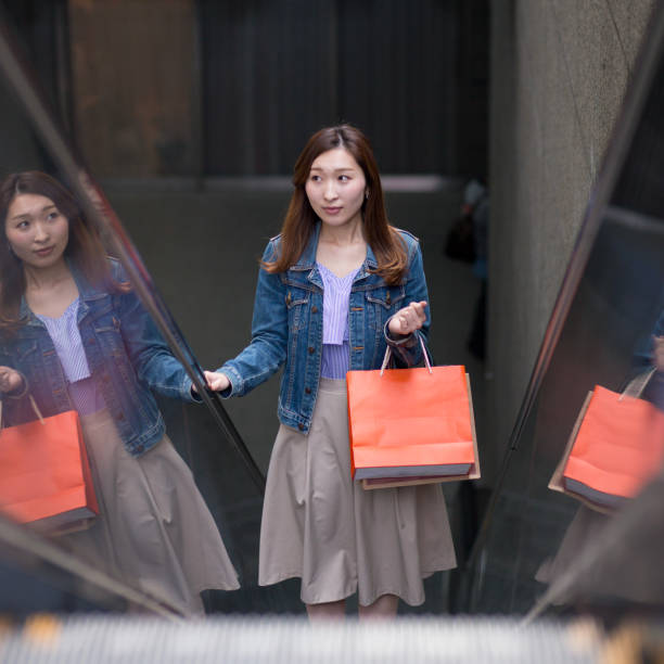istock Young woman moving up on escalator 901886954